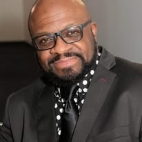 Marc Ivory, Gospel recording artist and pastor, holding a microphone and speaking at a pulpit