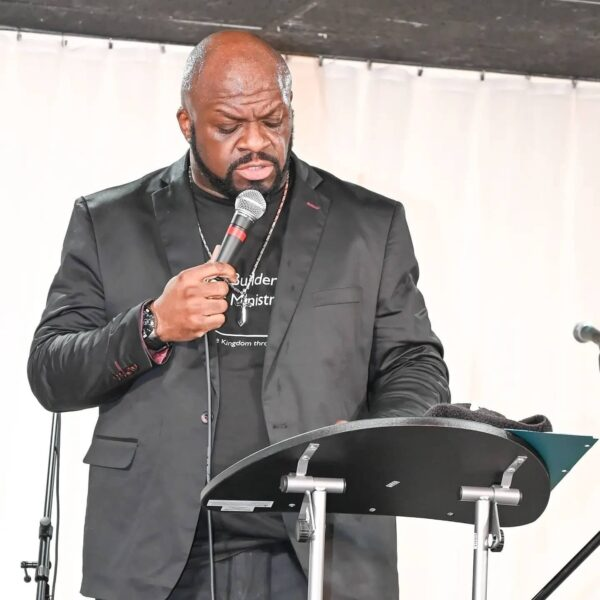 Marc Ivory, Gospel recording artist and pastor, holding a microphone and speaking at a pulpit