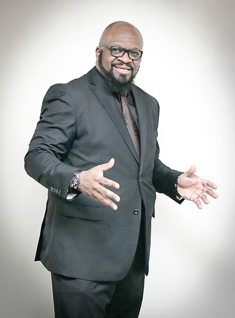 Marc Ivory, Gospel recording artist and pastor, holding a microphone and speaking at a pulpit